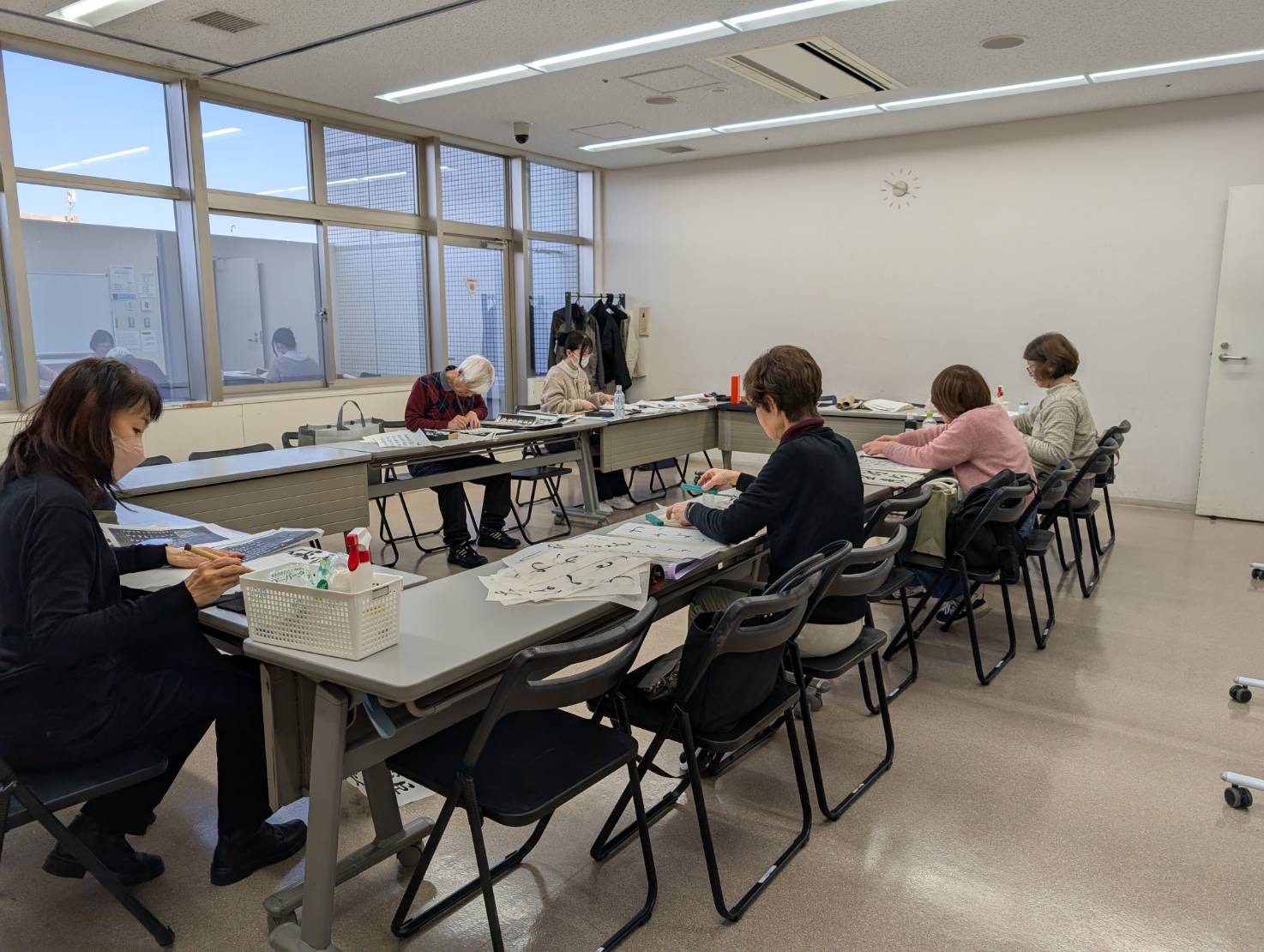 教室で複数の生徒が机に向かい書を学ぶ様子